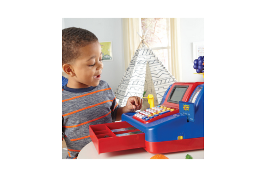 A little boy is pictured playing with the pretend cash register.