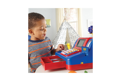 A little boy is pictured playing with the pretend cash register.