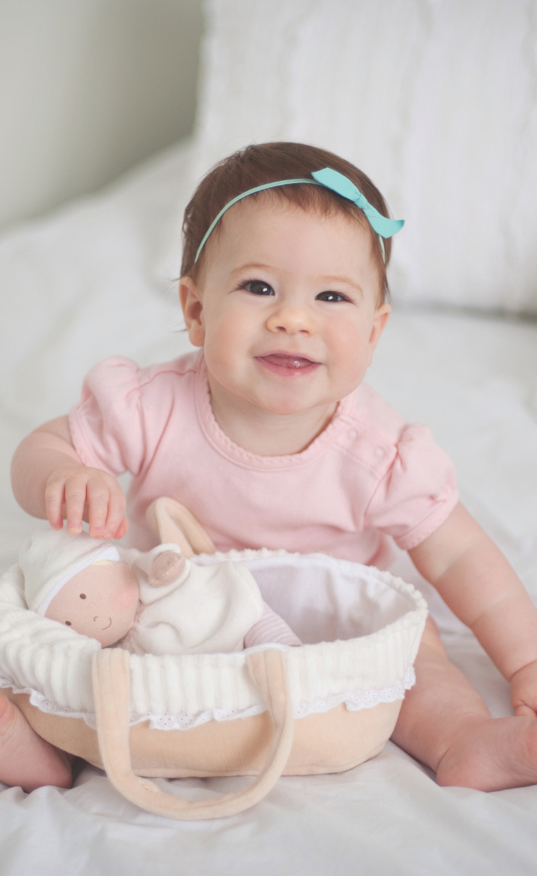 Baby playing with Baby Grace doll