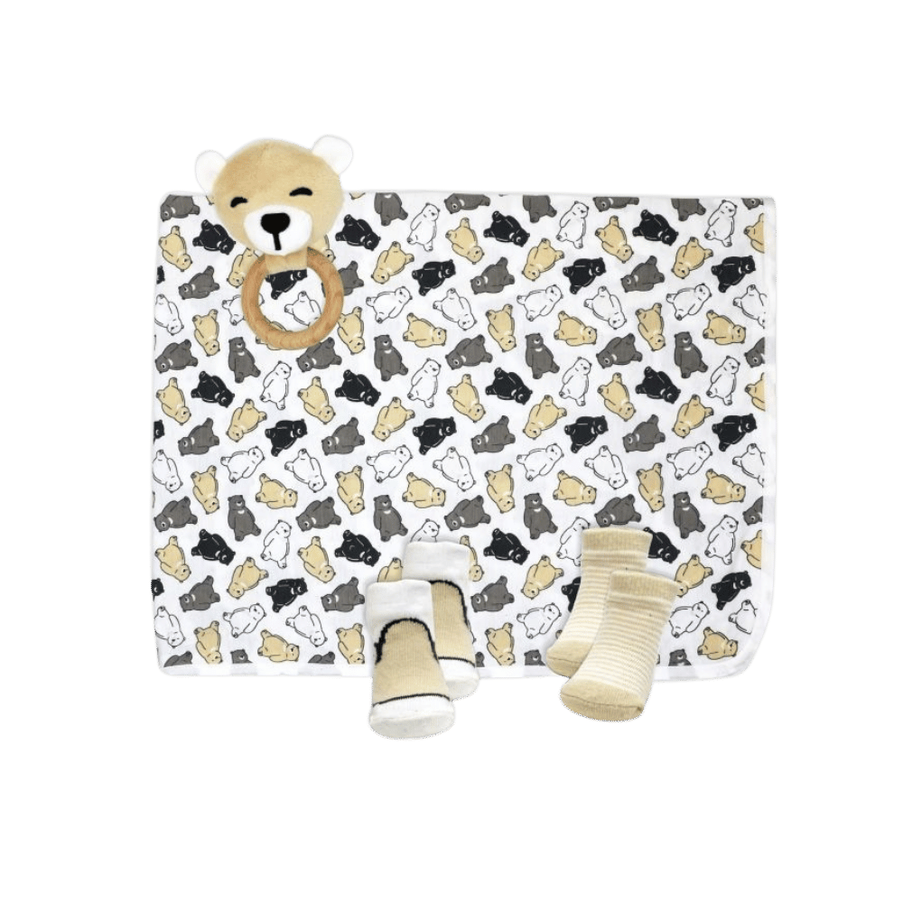 Knit swaddle set spread out on display to showcase each product, blanket, wood rattle and socks