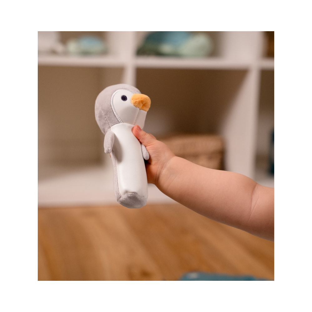 A baby's hand shown holding Martin the Penguin