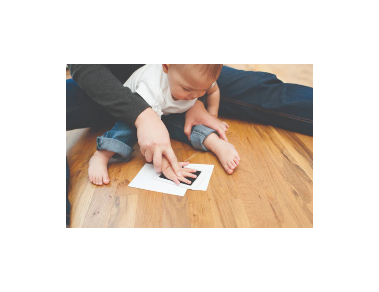 A photo of a parent and child doing the hand print with baby's hand.