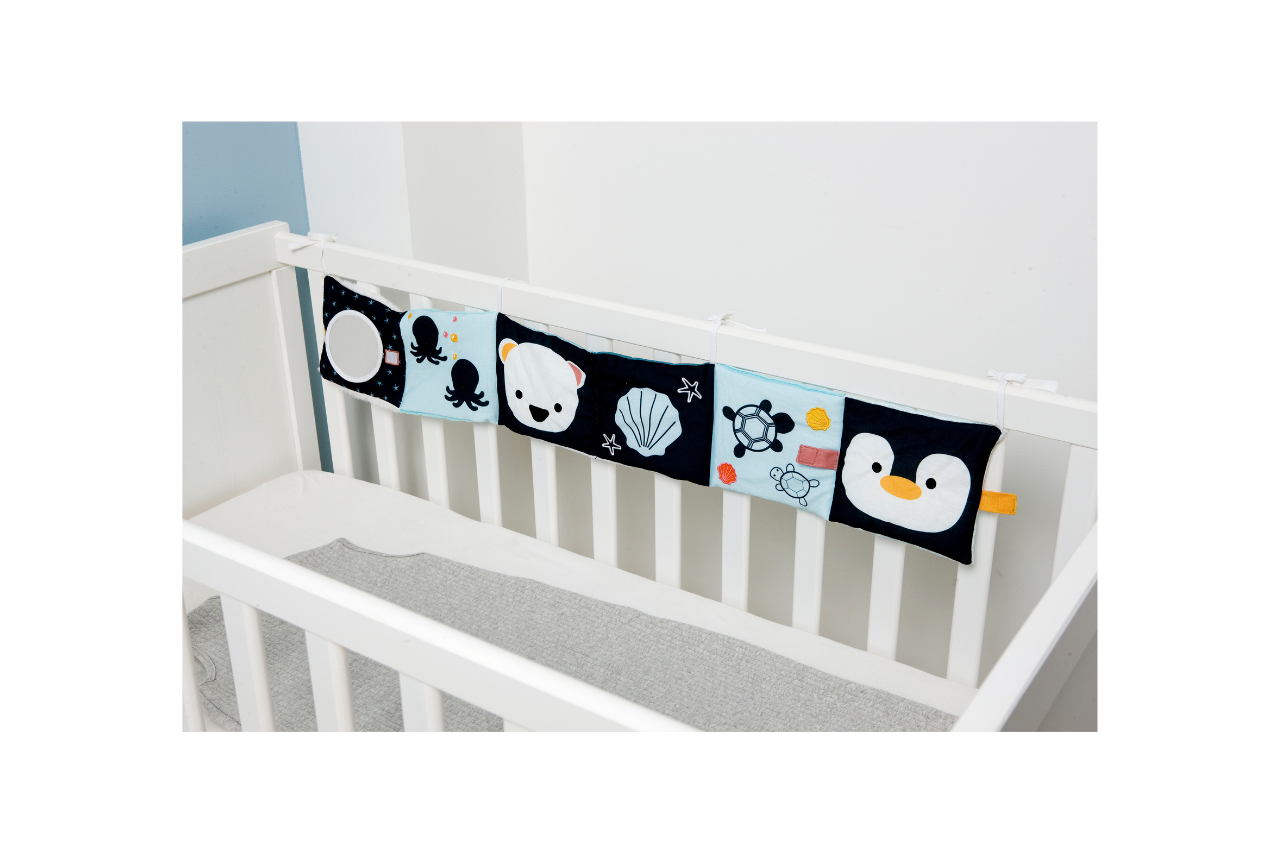 Ocean Soft Activity Book displayed on a crib/strung across the crib slats