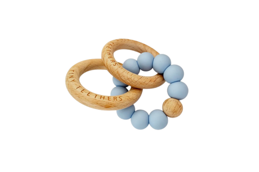 Soothe your baby with Tiny Teethers' pale blue coloured and wood rattle teething rings. Made from 100% silicone and beech wood.

Helps baby develop fine motor skills and strength by encouraging grasping, holding and pulling. Also helps with sensory needs by providing them with different textures to keep them stimulated.

Perfect for babies aged 3+months.