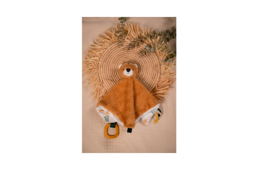 Tim The Tiger-Baby Comforter on a brown background laying on a hand woven tray with green plant branches as decoration